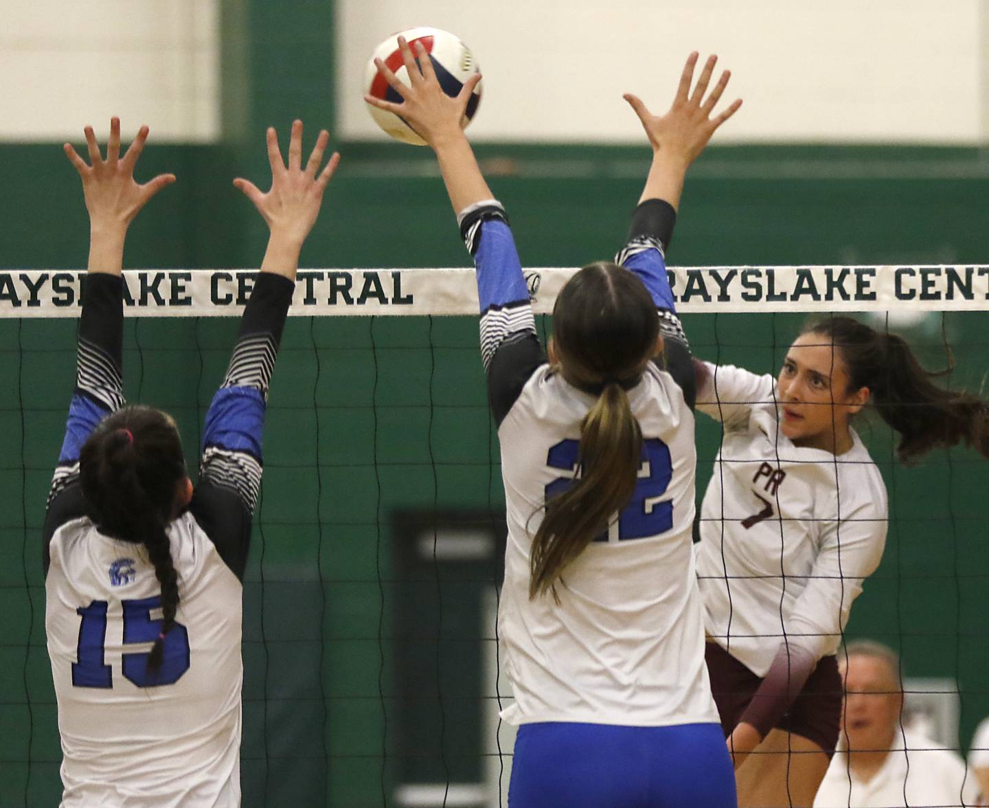 Prairie Ridge's Maizy Agnello (right) hits the ball between the block of St. Francis' Delaney Zamis (left) and Addy Horner (center) during the IHSA Class 3A Grayslake Central Supersectional volleyball match on Monday, Nov. 11, 2024, at Grayslake Central High School.