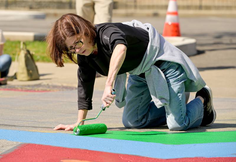 Jennifer Hammerli participates in the St. Charles Art Council’s “Paint the Riverside” to change out the street mural in the intersection of Walnut and Riverside Avenues on Saturday, May 10, 2025 in St. Charles.