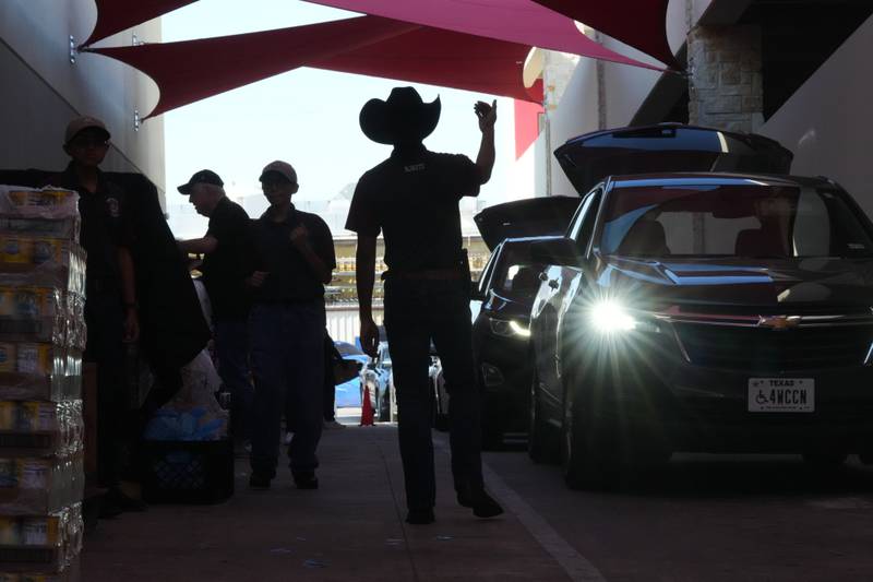 Aidan Tavor, center, directs traffic as volunteers help load vehicles during a food distribution at the San Antonio Food Bank for SNAP recipients and other households affected by the federal shutdown, Thursday, Nov. 6, 2025, in San Antonio. (AP Photo/Eric Gay)