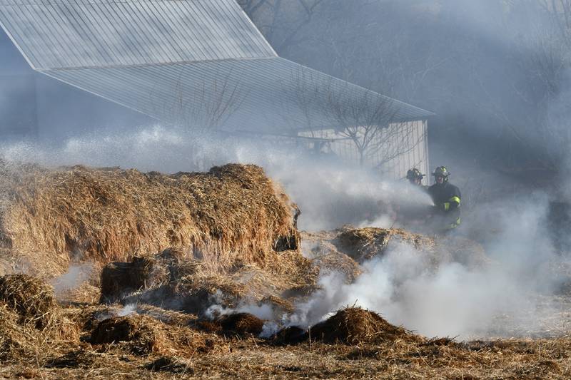 Firefighters battled a hay bale fire at a farm on West Pines Road between Polo and Oregon on Monday, Feb. 23, 2026. Here, firefighters spray water on the burning bales.