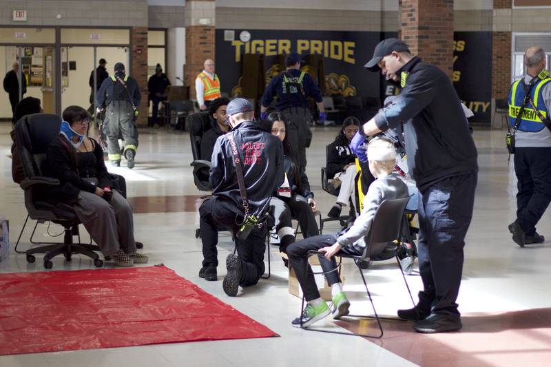 Paramedics providing medical care for student actors inside Joliet West High School on Tuesday, March 25, 2025, for a staged emergency drill simulating the aftermath of a gas explosion. The actors near the red mat are considered the most critically injured patients who must be treated first as part of the exercise.
