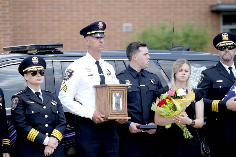 Kane County Sgt. Nick Wolf holds the remains of Kane County Sheriff K9 Hudson as Undersheriff Amy Johnson (far left), Hudson’s handler Luke Weston and his wife, Rachel, during a funeral in honor of the Dutch shepherd, who lost his life in the line of duty last month, on Thursday, June 1, 2023 at Kaneland Harter Middle School in Sugar Grove.