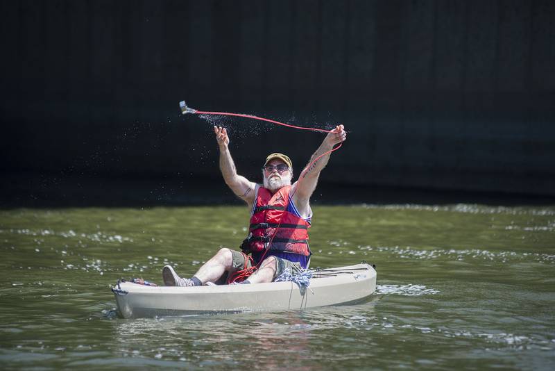 Mark Stach casts the line with a magnet from his kayak on July 21. When the line hits the bottom of the Rock River in Dixon, he’ll slowly pull it back as it drags along the river bed.