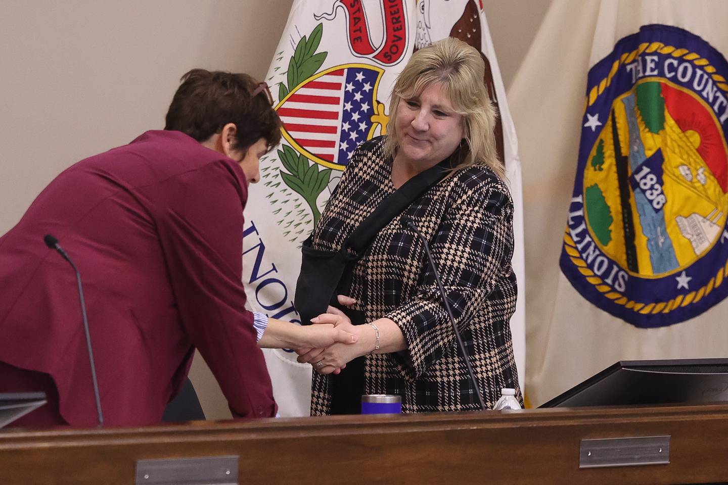 Will County Executive Director Jennifer Bertino-Tarrant greets Annette Parker as she takes her sit for the first time as the new Will County Clerk at the Will County Board Meeting on Monday, Dec. 2, 2024 in Joliet.