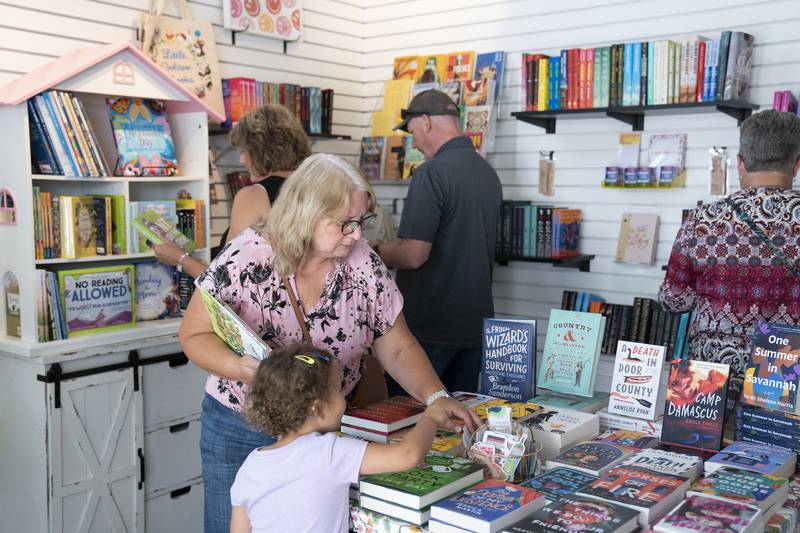 Kim Ziegler, of Ingleside, shops at Little Bean Books with her granddaughter Quinn Larson, 3, during the grand opening and ribbon cutting of the new McHenry Riverwalk Shoppes in downtown McHenry on Friday, July 21, 2023.