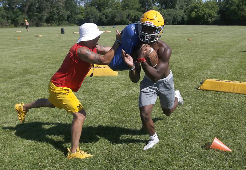 Running back Antonio Brown is hit with a pad by coach Brian Zimmerman as the do a running drill during football practice Monday, June 20, 2022, at Jacobs High School in Algonquin.