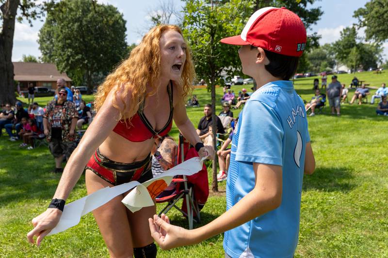 (left to right) Maggie Lee rips sign that reads "Maggie Lee Sucks" infant of fan Rocco Affrunti at the Taste of the Illinois Valley DreamWave Wrestling event on Saturday, August 2, 2025 at Centennial Park in Peru.