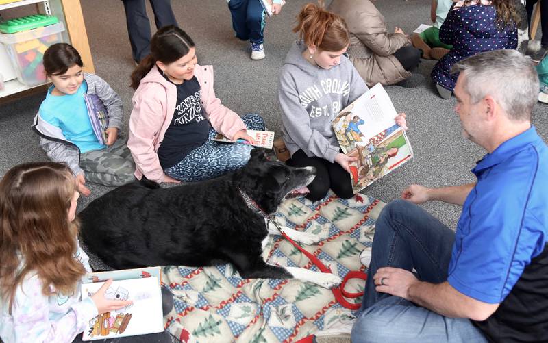 Olivia and Luciana Salto (left) listen as Mya Pratl reads to Comet and Jeff Corirossi (both from the Fox Valley Therapy Dog Club) during Read With Rover at the Sugar Grove Library on Saturday, March 11,2023.