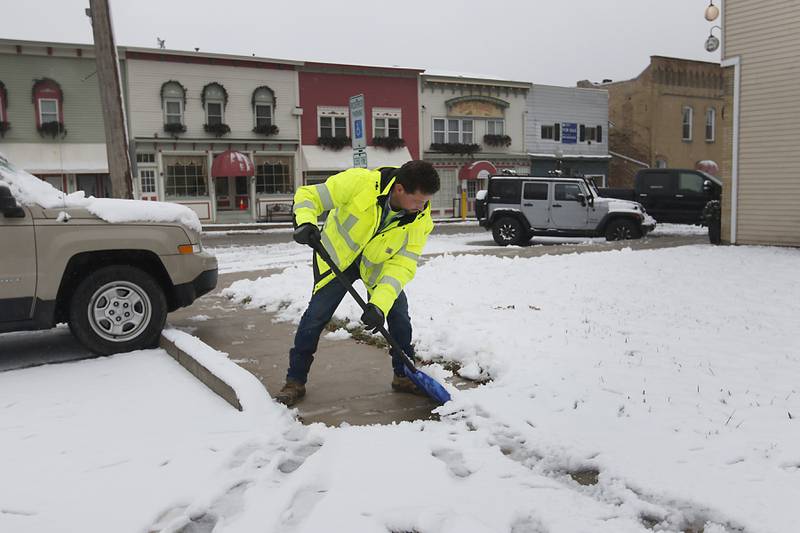 Matt Kaminsky with the Village of Richmond Public Works Department, shovels snow off a public sidewalk on Friday,  Dec. 9, 2022, in downtown Richmond. Areas of McHenry County received a couple of inches on snow after a winter storm moved through the county.