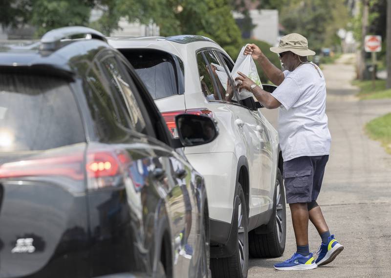 Gordon Harris, chaplain for Post 296, delivers meals to waiting cars Monday, Aug. 5, 2024 in Sterling.