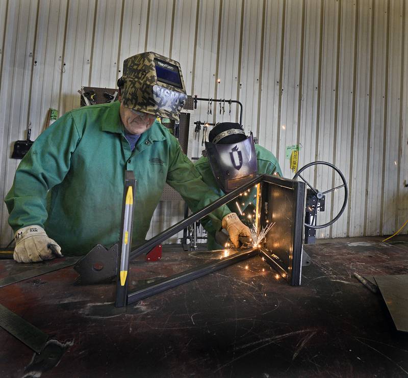 Illinois Valley Community College welding instructor Mike Merman guides welding student Zach Znaniecki as he adds a weld to a side table Wednesday, June 28, 2023, at IVCC during its Summer Camp program.
