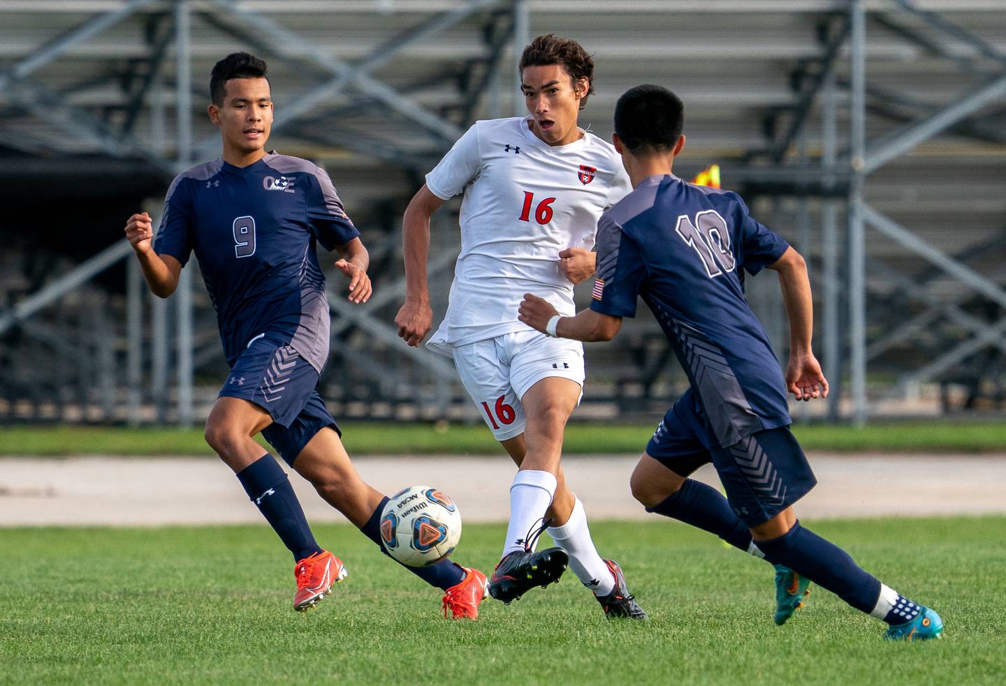 Oswego’s Benjamin Sobecki (16) passes the ball between Oswego East's Dupablo Parodis-Yu (9) and Israel Torres (10) during a soccer match at Oswego East High School on Monday, Sep 26, 2022.