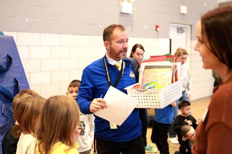 Grace McWayne Elementary School teacher Chad Clarey directs students, volunteers and colleagues during a visit to the Marklund Hyde Center in Geneva, where they made valentines and read to the clients.