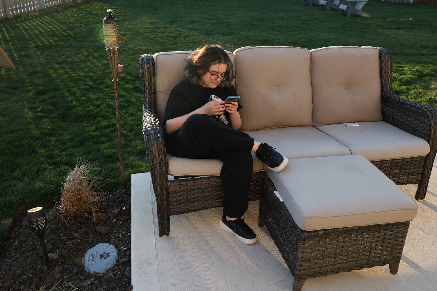 Lizzie Reyes checks her phone while hanging out in her backyard on Wednesday, April 12, 2023 in Joliet.