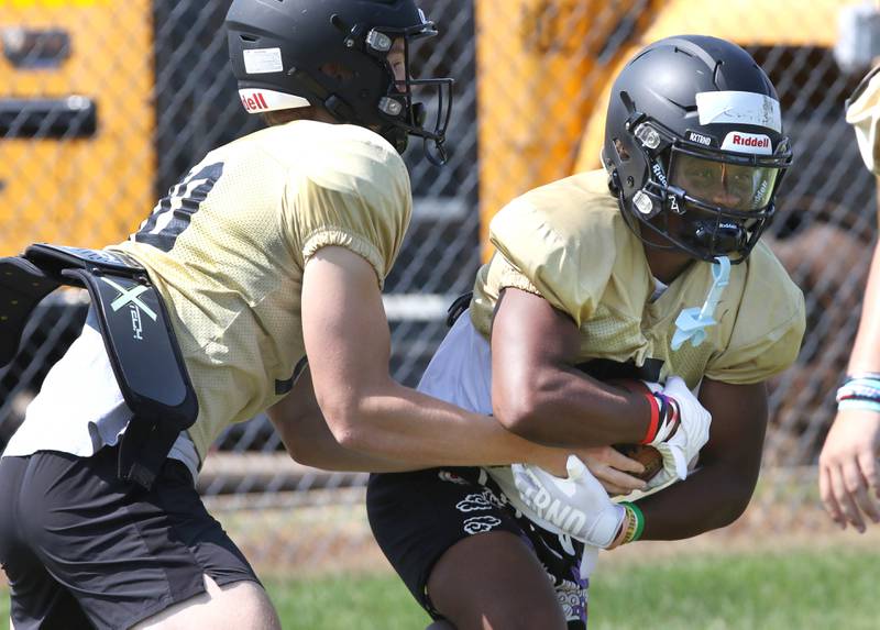 Sycamore quarterback Burke Gautcher hands the ball off to running back Tyler Curtis during practice Monday, July 17, 2023 at the school.