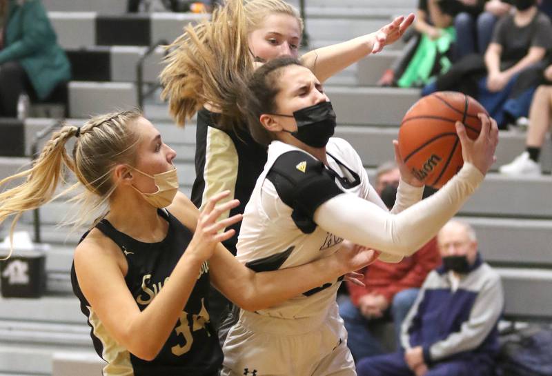 Kaneland's Megan Noel grabs a rebound between two Sycamore defenders during their game Tuesday, Feb. 1, 2022, at Kaneland High School in Maple Park.
