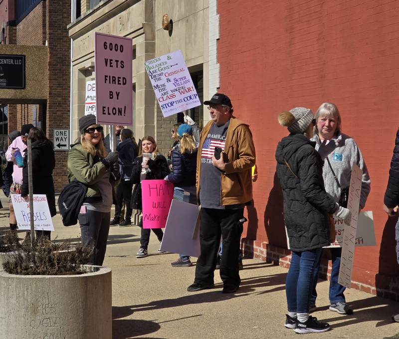Residents held signs along Madison Street on Saturday, March 8, 2025, ahead of the March for Democracy in downtown Ottawa.
