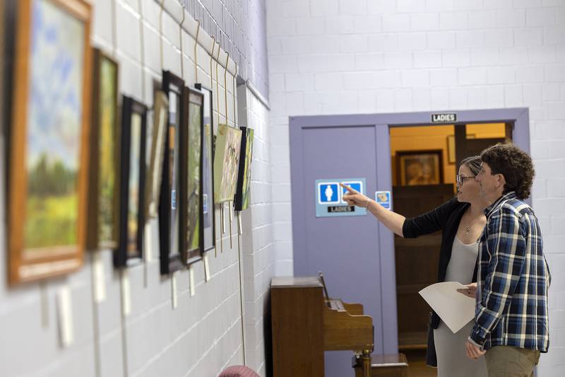 Hannah Tucker and Brian Carroll look over the display of paintings Thursday, April 3, 2025, at the Phidian Art Club’s 76th art show. The show was held at the Loveland Community House in Dixon.