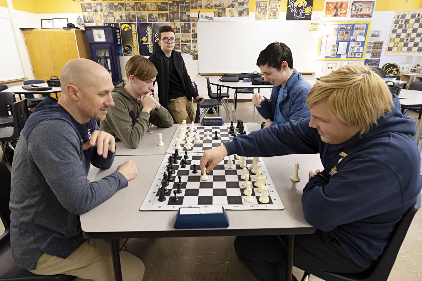 Sterling High School chess instructor Joel Penne plays a team chess game with players Kinnick Kyarsgaard (left), Nate Lobdell and Xander Knowles during an off season activity hour at the school.