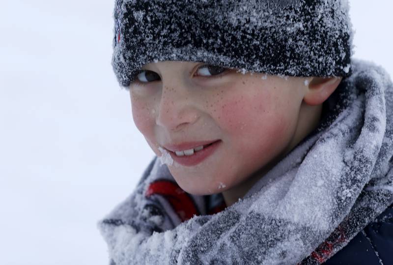 Brody Perocho, 8, of Crystal Lake, is covered with snow as he sleds at Veteran Acres Park the afternoon of Monday, Jan. 24, 2022, after McHenry County received a fresh snowfall.