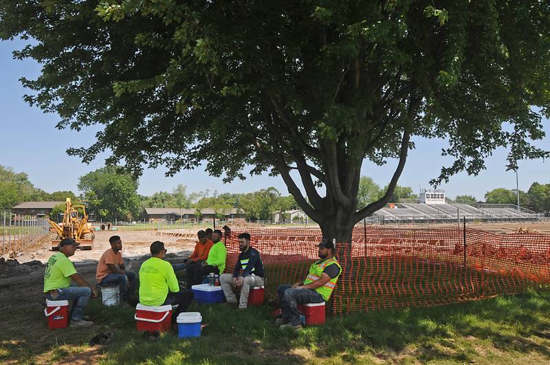 Workers from Herrera Construction eat lunch under the shade of a maple tree on Tuesday, June 14, 2022, while working on upgrading McCracken Athletic Field in McHenry. Temperatures in the McHenry County area reached the mid-90’s.