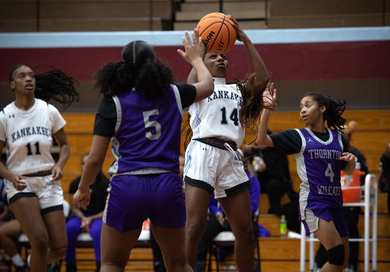 Kankakee's Jasyia Wesby, center, takes a shot as Thornton's Cymone Maxey, left, defends in a game on Thursday, December 4, 2025.