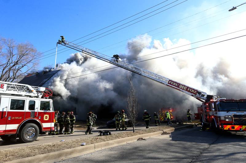 Heavy smoke billows from the roof  as firefighters dump water on a fully engulfed home in the 800 block of Bucklin Street on Friday, Jan. 23, 2026 in La Salle.