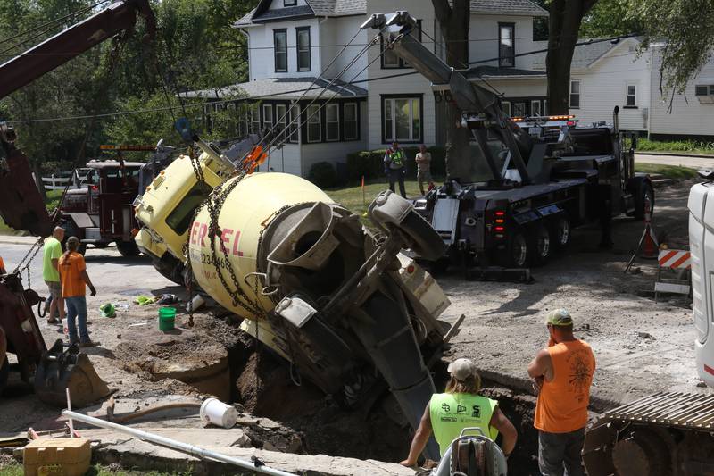 Crews with Scholles Body Shop use tow trucks to lift a cement truck out of a sinkhole on Tuesday, Sept. 2, 2025 at the intersection of Pulaski Street and 6th Streets in Peru.