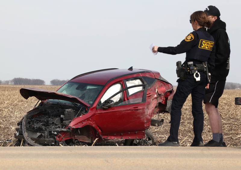 A DeKalb County sheriff’s deputy works the scene where a badly damaged vehicle sits in a cornfield on the east side of Somonauk Road south of McGirr Road Wednesday, March 25, 2026, after a two vehicle crash near Hinckley.
