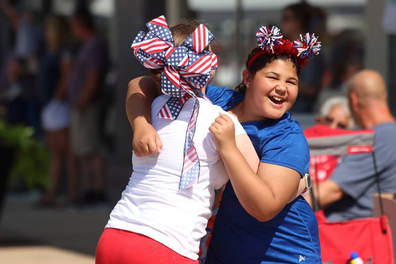 Ariah Boyd, 10, right, shares a hug with Annabella Kirksey, 10, as they wait for the Huntley Independence Day Parade along Main Street in Huntley on Friday, July 4, 2025. Both are from Huntley.