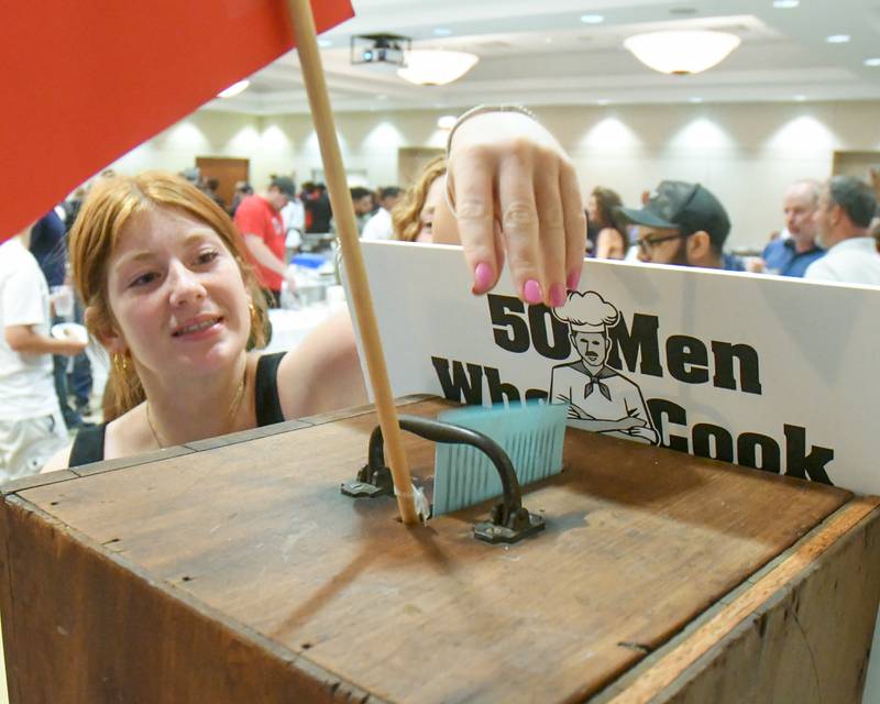 Taylor Tilstra of Sycamore drops her ballot into the voting box after sampling food during the 20th anniversary of 50 Men Who Cook, an annual fundraiser hosted by CASA DeKalb County at the Barsema Alumni and Visitors Center at Northern Illinois University in DeKalb on Saturday, Aug. 10, 2024.