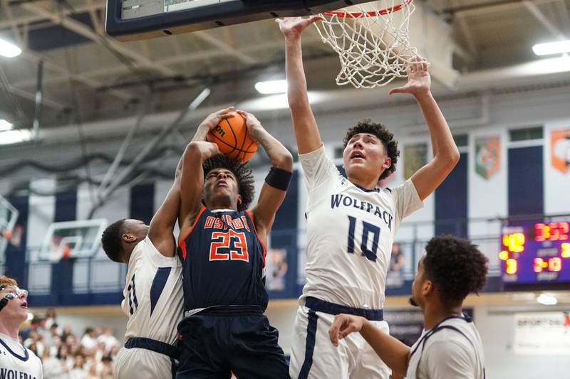 Oswego East's Reginald McWaine (11) and Damien Lewandowski (10) defend the paint against a shot by Oswego’s Dasean Patton (23) during a basketball game at Oswego East High School on Saturday, January 14, 2017.