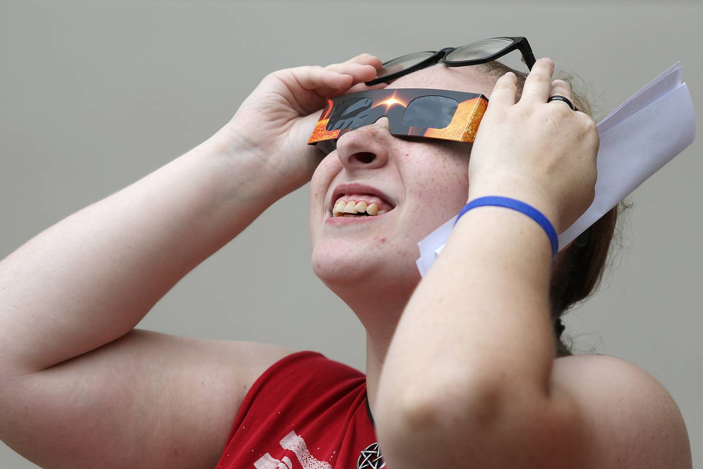 Tristan Jensen of DeKalb, 17, looks up, searching for the sun through the cloudy sky on Monday, Aug. 21, 2017 at the DeKalb Public Library in DeKalb. Jensen was one of the lucky 60 people to arrive at the library in time to get a free pair of solar eclipse glasses for free before supplies ran out.