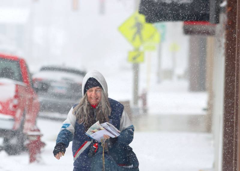 United States Postal Service letter carrier Toni Boyd works along State Street during a snowstorm in Marengo on Saturday, November 29, 2025.