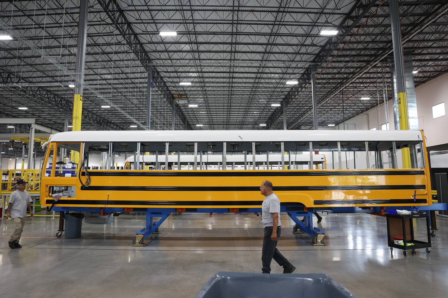 A worker walks past the shell of a bus at the Lion Electric manufacturing facility on Friday, July 21st, 2023 in Joliet.