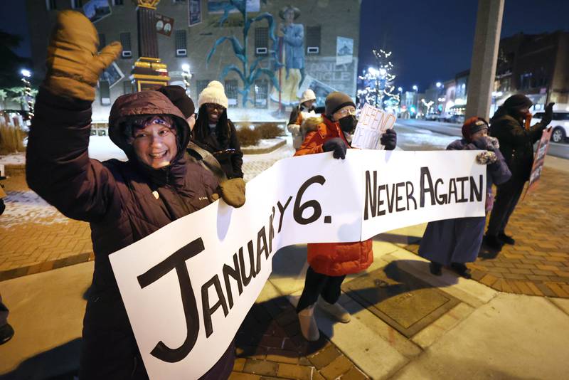 Cynthia De Seife, (left) a member of Responsive Engagement Activating Civic Talent, along with other demonstrators wave at passing cars Friday, Jan. 6, 2023, during a Stand for Democracy demonstration at Memorial Park in downtown DeKalb. The second annual event was held to affirm the attendees commitment to American democracy.