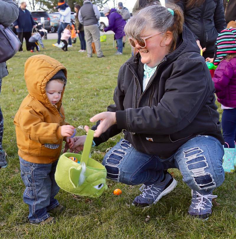 Eli Mosley, 18 months, puts an Easter egg in his basket, held by Jodeen Clark-Beyer, during the Easter Egg Hunt at the Lion’s Club in Elburn on Saturday, April 9, 2022.