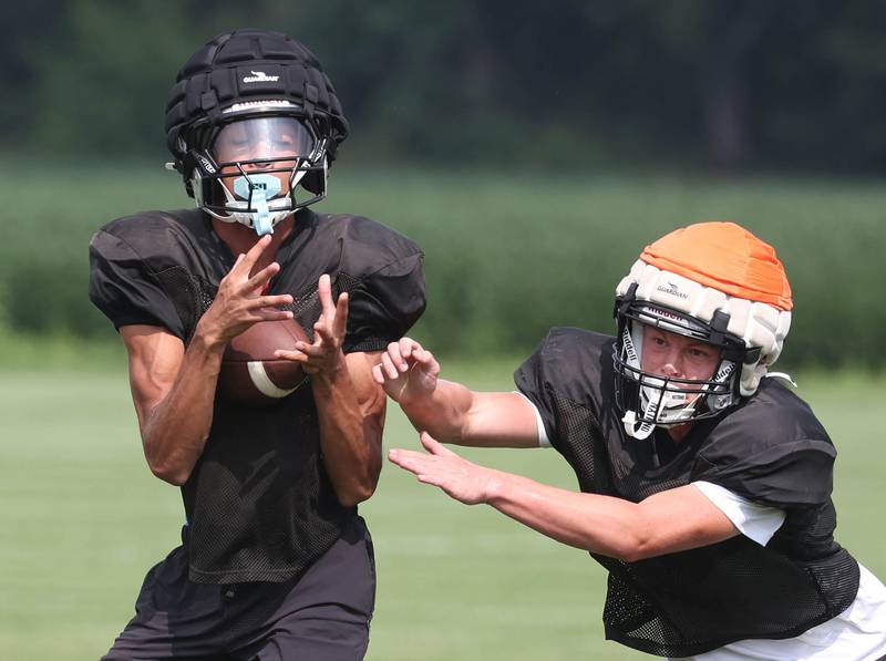 Kaneland’s Evan Frieders (left) catches a pass Monday, Aug. 18, 2025, during practice at the school in Maple Park.