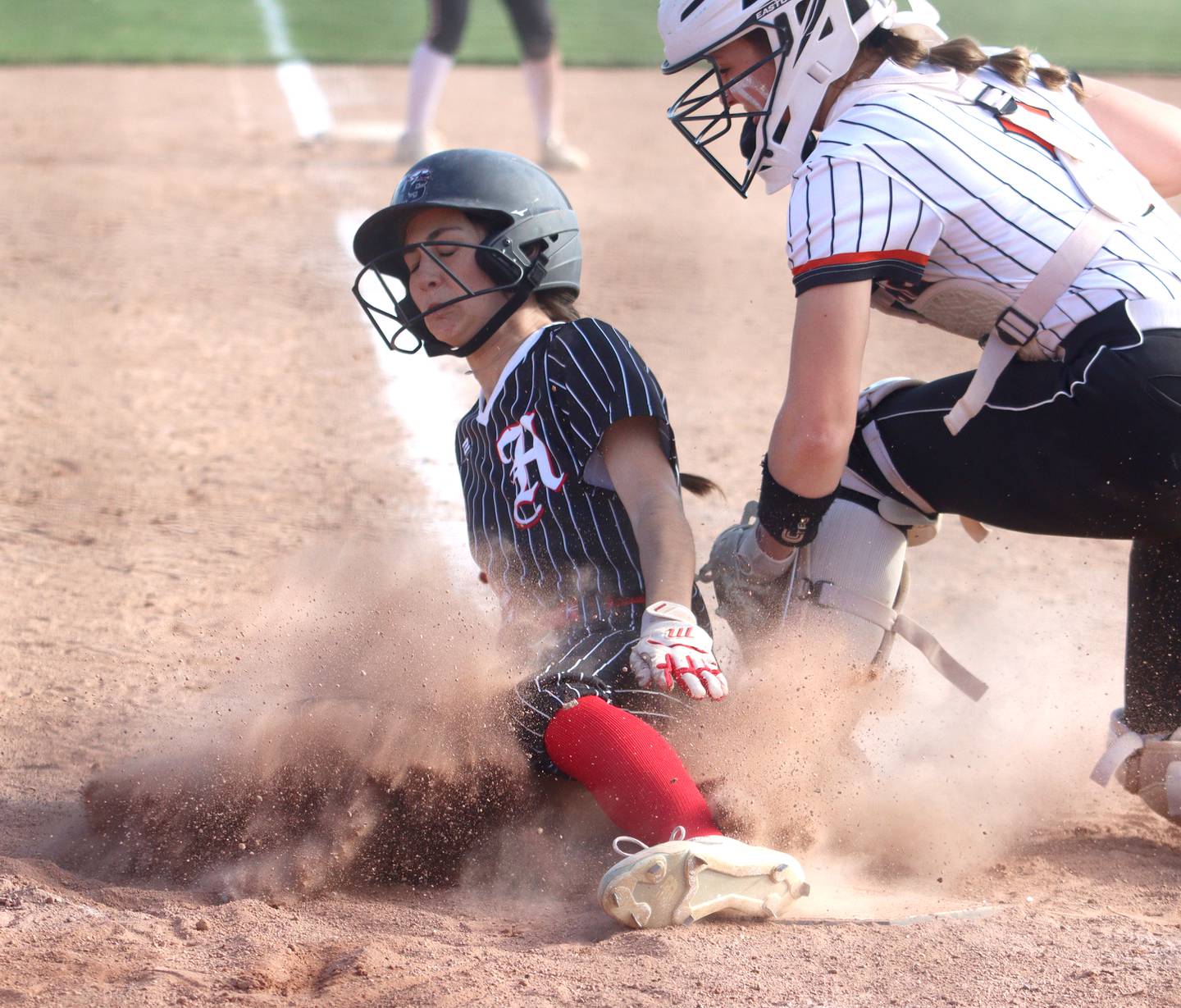 Huntley’s Katie Mitchell scores safely under the tag of McHenry’s Emma Stolzman on Friday in Huntley.