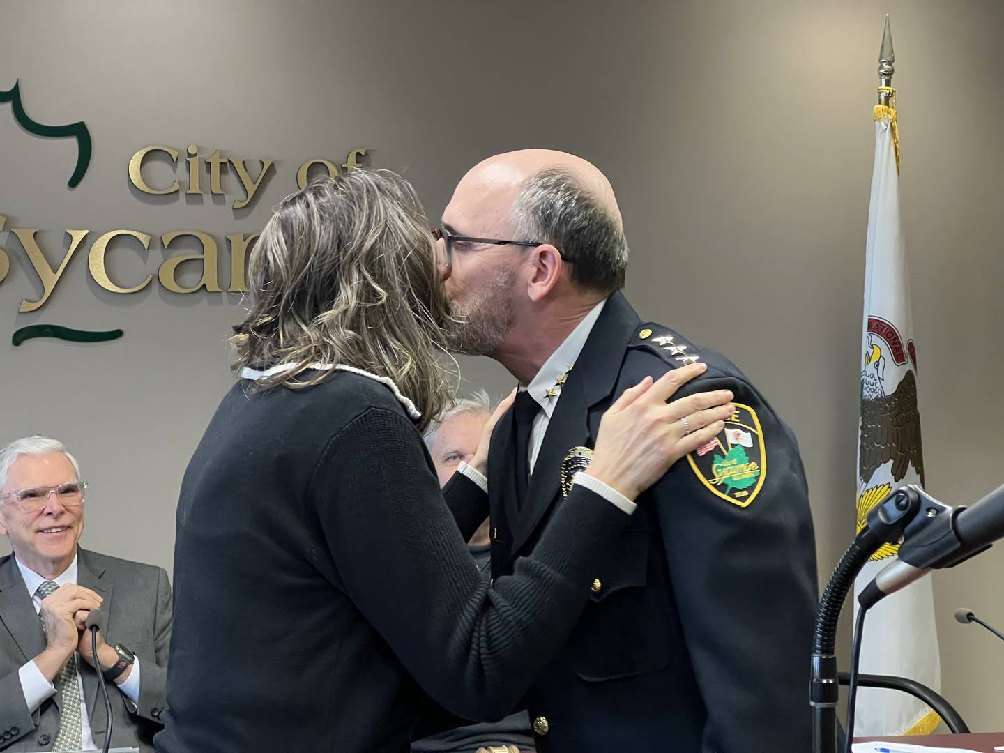 Sycamore Police Chief Erik Mahan kisses his wife, Cindy Mahan after she pinned on his new badge on March 17, 2025, in front of Sycamore City Council and city lawyer Keith Foster.