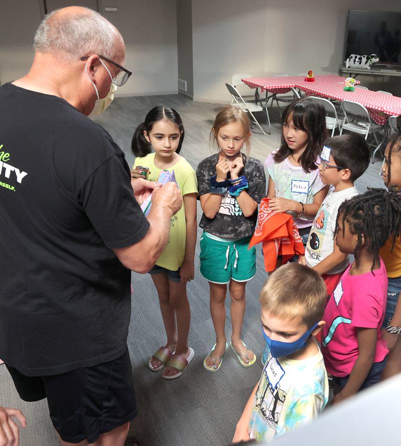 A volunteer gets participants ready for the first activity Monday, July 11, 2022, during a session of Summer Reading Vacation put on by Neighbors' House in DeKalb in conjunction with the DeKalb County Farm Bureau. Christ Community Church is hosting the event this week in their outreach center on North 6th Street in DeKalb.