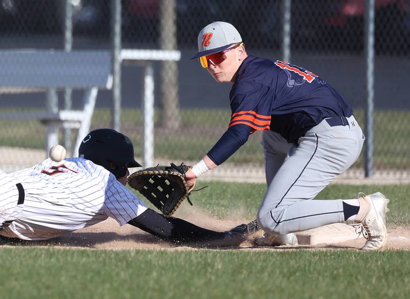 Naperville North’s Lawton Close takes the throw as DeKalb's Cole Latimer dives back to first safely Tuesday, April 15, 2025, during their game at DeKalb High School.