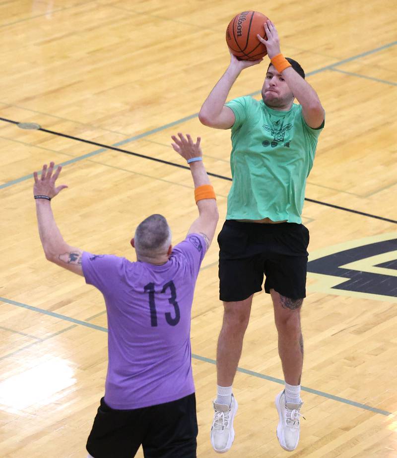 Fire/Police team member Grayson Zepeda shoots a three pointer over Sycamore School Staff team member Jeff Hilmer Thursday, Dec. 19, 2024, during the Heroes on Hardwood basketball game at Sycamore High School. The basketball game, which is a fundraiser for the Spartan Food Pantry, pits a team of Sycamore first responders against a squad of Sycamore School District 427 staff.