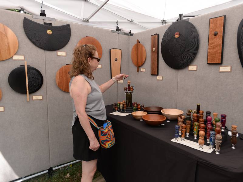Lisa Schwarz of Glen Ellyn takes a closer look at some of the wood bottle openers during the Glen Ellyn Art Festival on Sunday, Aug 24, 2024 at Lake Ellyn.