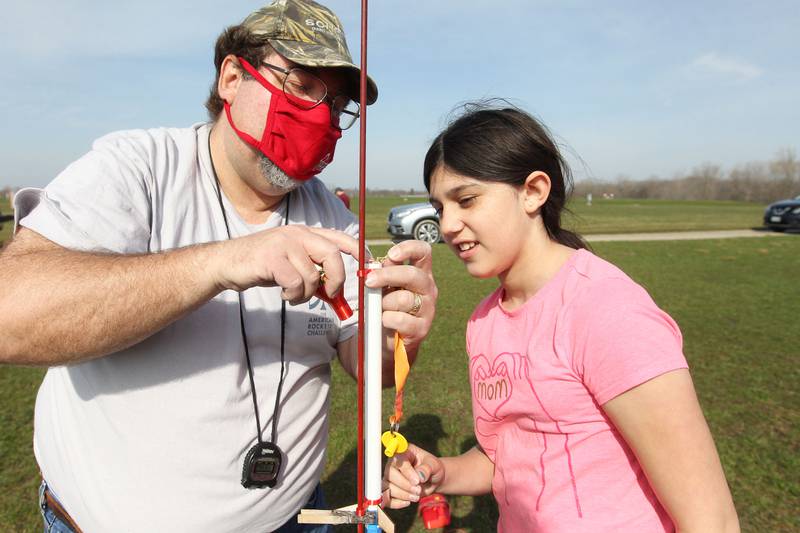Bob Zurek, of Antioch, advisor, helps Rosa Lozano, 10, of Lake Villa, a member of the Prince of Peace Redhawk Rocketeers team, launch her eggloft rocket at the Tim Osmond Sports Complex in Antioch.