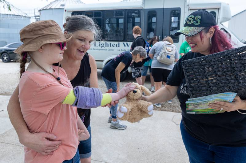 Michelle of lighted way holds Mackenzie as she grabs stuffed animal from Laura Loch on Friday, June 27, 2025 at Loch Countryside Kennel in Peru.