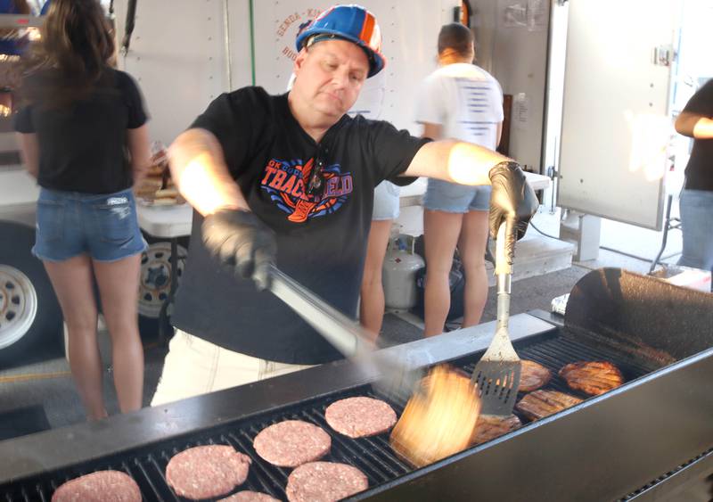 Steve Brust, also know as Hard Hat Steve, is busy flipping burgers at the Genoa-Kingston High School Athletic Boosters Club food booth during Genoa Days, Wednesday, June 7, 2023, in downtown Genoa. The festival continues through Saturday.