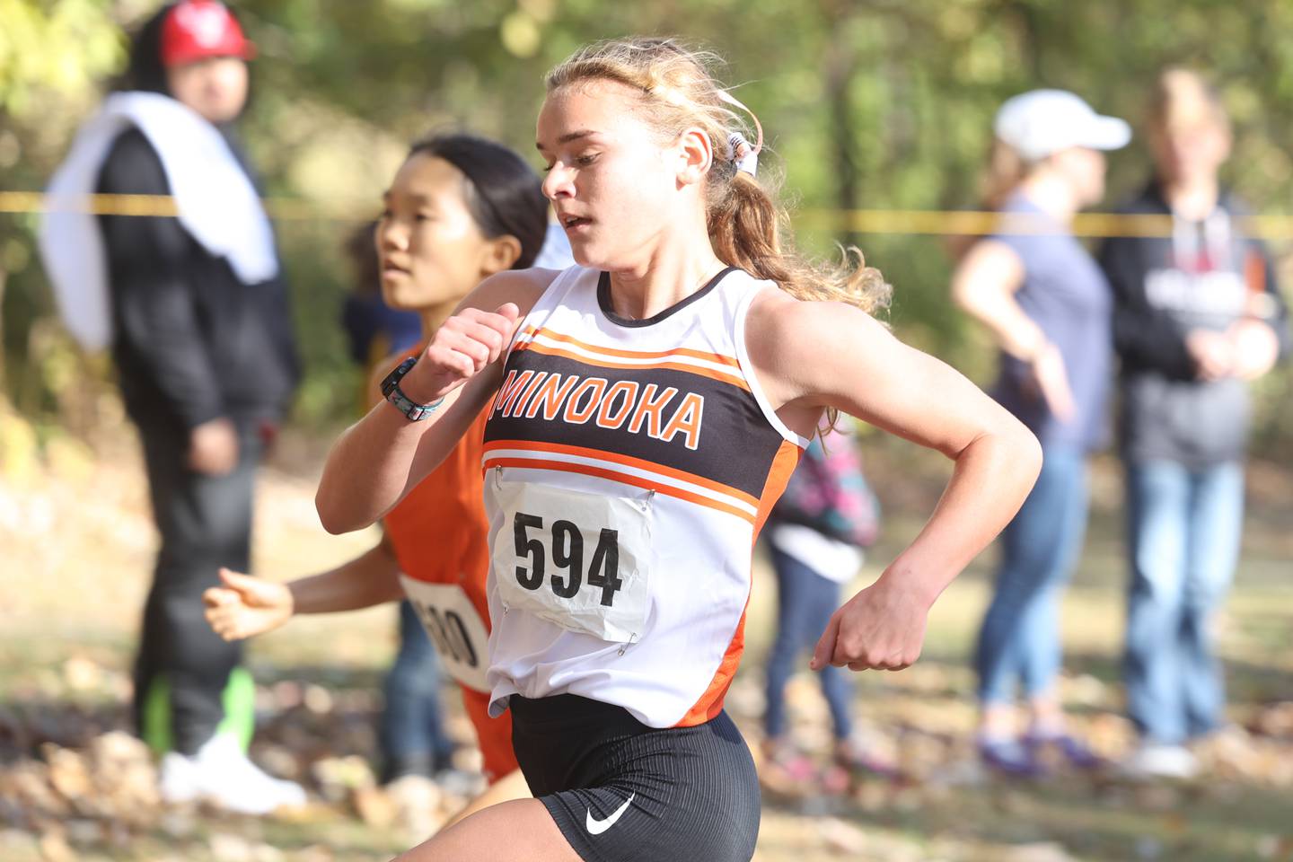 Minooka’s Ella McCollum passes Oswego’s Kelly Wong yards away from the finish line to finish 4th in the Girls Cross Country Class 3A Minooka Regional at Channahon Community Park on Saturday.