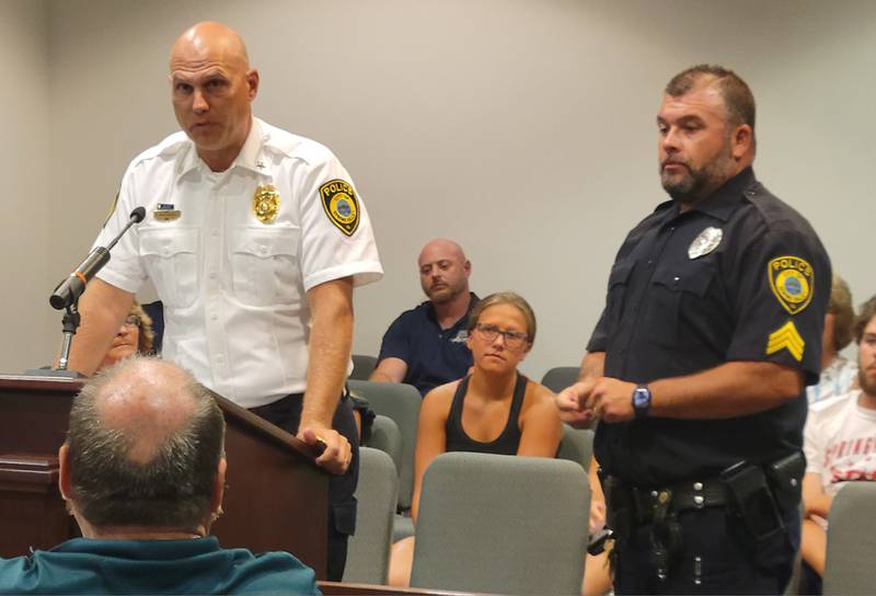 Spring Valley police officer Josh Pellegrini (right) listens as chief Adam Curran lists the reasons for Pellegrini's promotion to the rank of sergeant at the Spring Valley City Council meeting on Monday night.