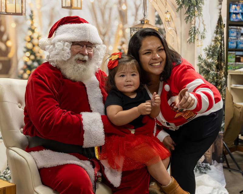 (from left) Santa, Josie Lopez and mother Alicia pose for photo at the annual Christmas in the Valley on Saturday, November 15, 2025 at the Cosgrove Distributors in Spring Valley.
